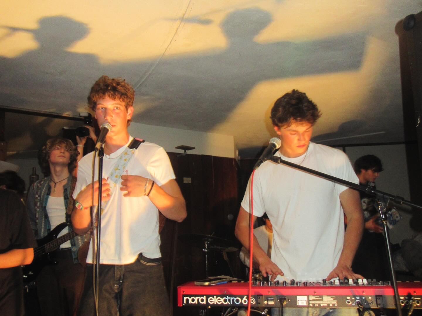 Vocalist and keyboardist performing under low light with their shadows cast on the ceiling