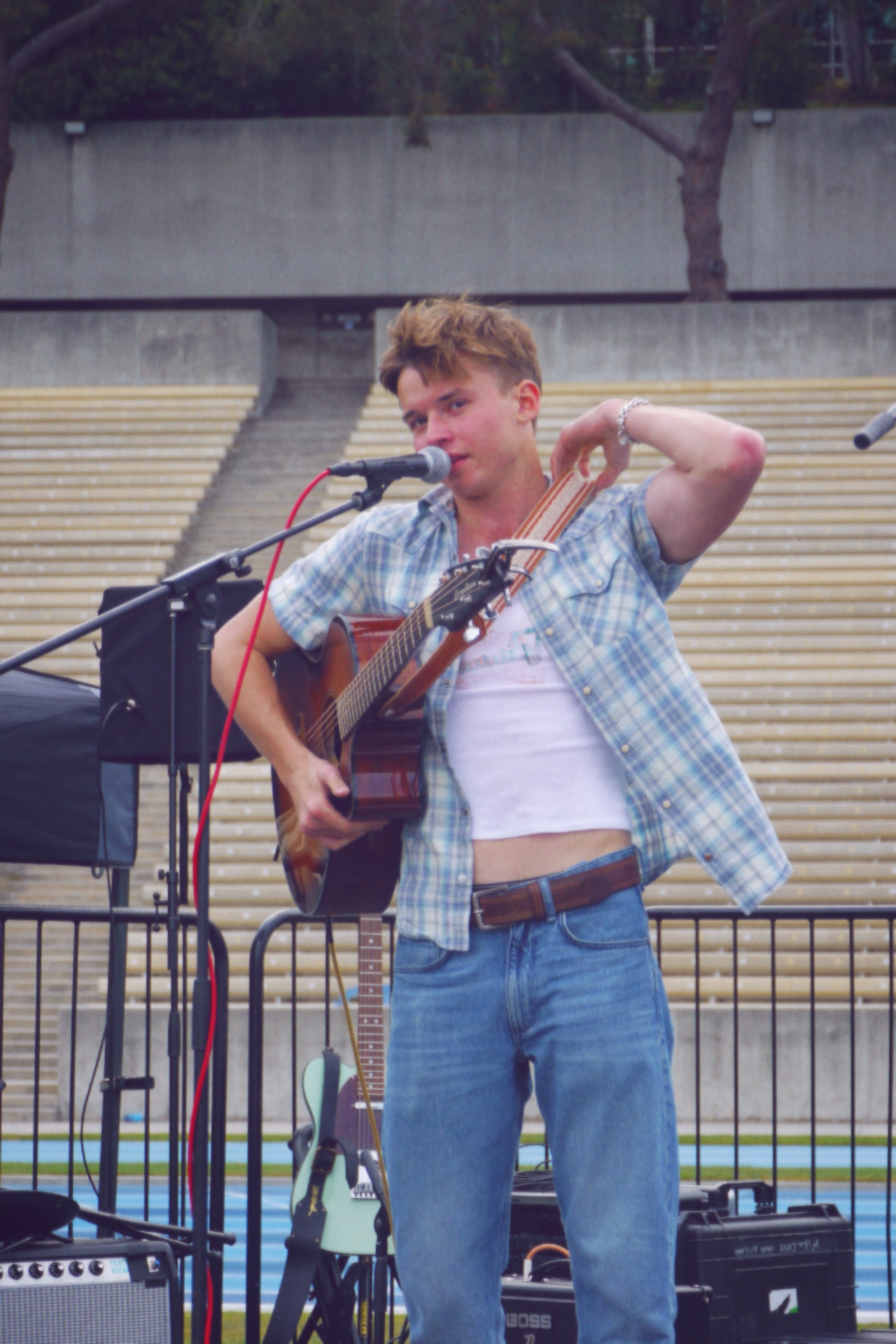 Singer with acoustic guitar at the microphone in Drake Stadium