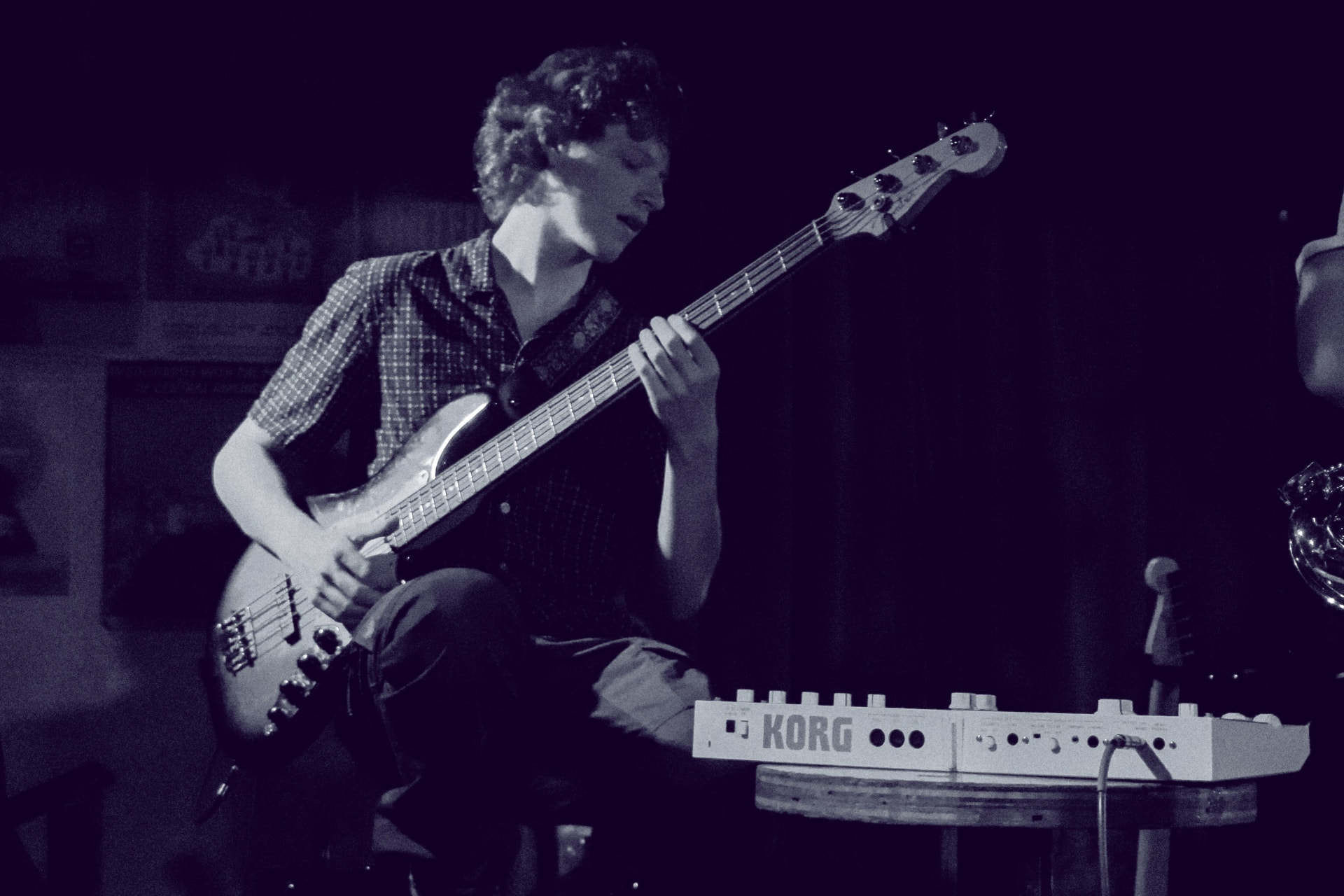 Black and white shot of the bassist playing under dark stage light